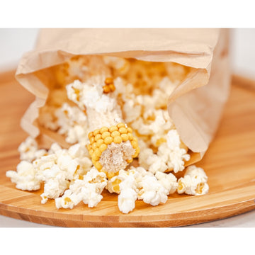 Popcorn spilling out of a paper bag onto a wooden surface.